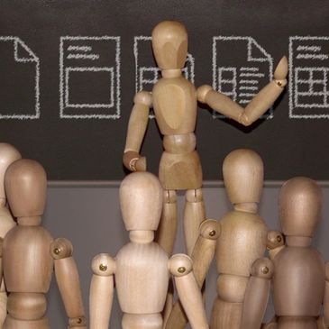 Photo illustration - Teacher and students (artist’s mannequins) view design sketches on a blackboard