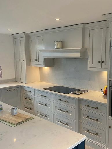 Modern kitchen with white cabinets and marble countertops under soft lighting.
