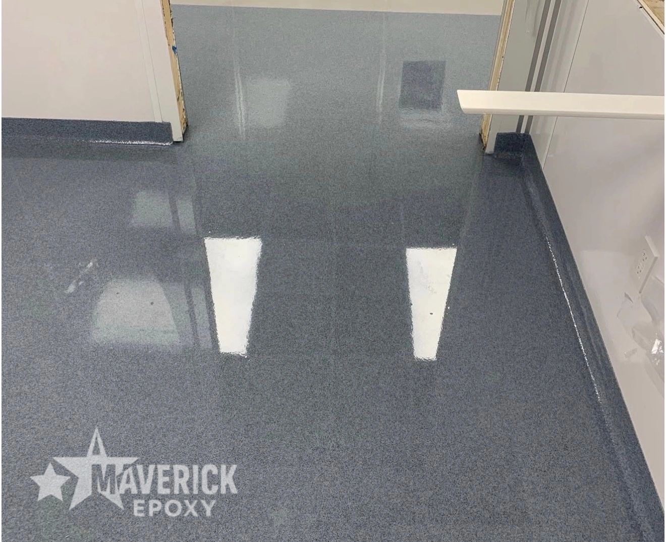 Glossy gray epoxy floor with reflections, labeled Maverick Epoxy.