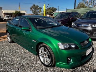 Green Holden Commodore parked on gravel.