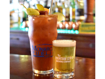 Two drinks on a bar counter: a Bloody Mary and a small beer.