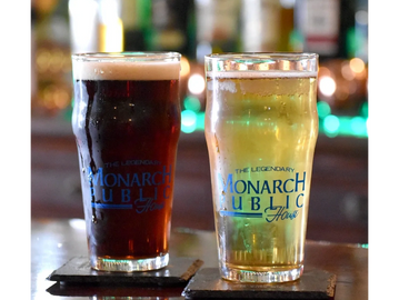Two glasses of beer, one dark and one light, on coasters at a bar.
