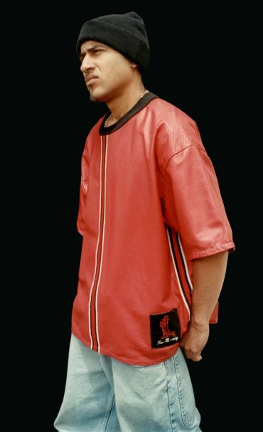 Man in red shirt and black hat posing.