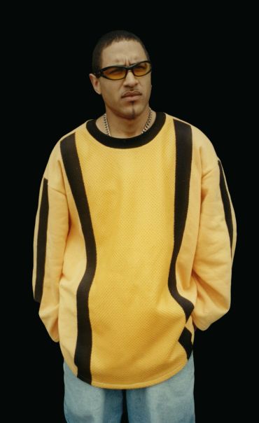 Man in oversized yellow sweater with black stripes and sunglasses.