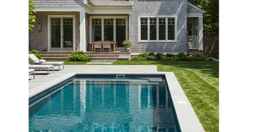 Modern house with a swimming pool and patio furniture in a green backyard.