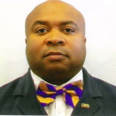 Man wearing a colorful bow tie and formal suit against a plain background.