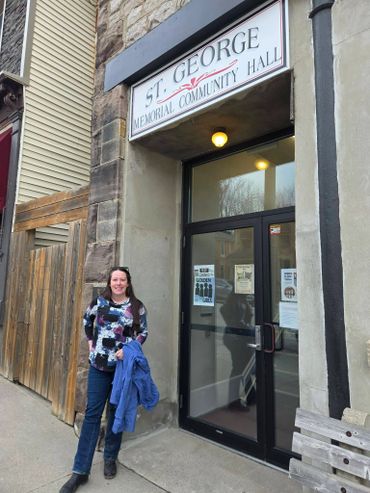 Woman standing outside St. George Memorial Community Hall entrance.