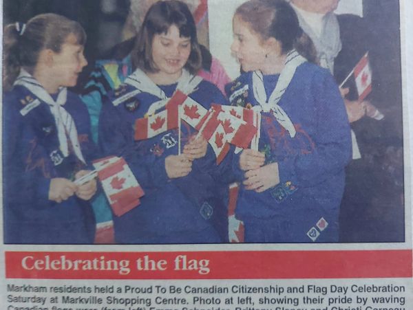 Girls in blue uniforms holding Canadian flags at a celebration.