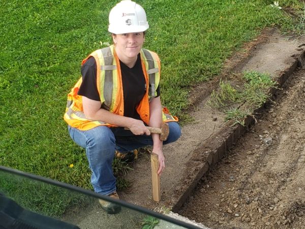 Person in safety gear working on soil edge.