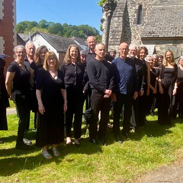 Group of people dressed in black standing outside near a church on a sunny day.