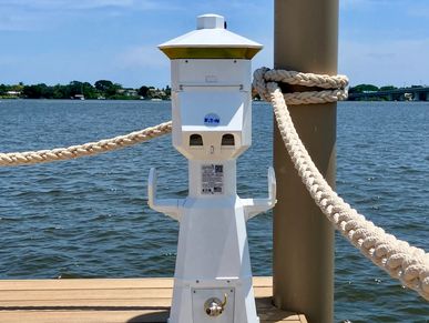 White electrical or water pedestal on a marina dock against water.