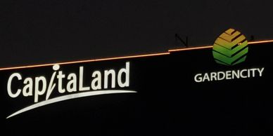 Illuminated CapitaLand and Garden City signs at night.