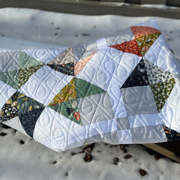 Colorful patchwork quilt with geometric patterns on a snowy background.