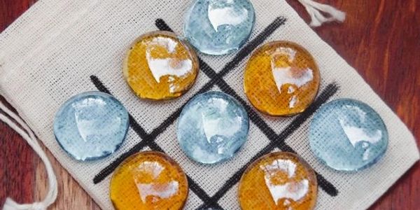 Tic-tac-toe game with glass stones on a cloth bag.