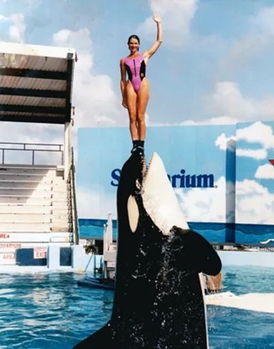 Marcia Davis at Seaquarium atop Toki, a killer whale
