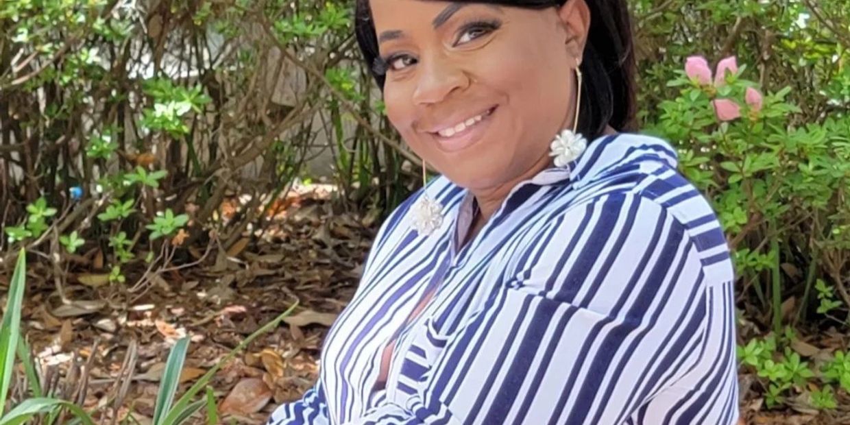Smiling woman outdoors in a striped shirt with floral earrings.