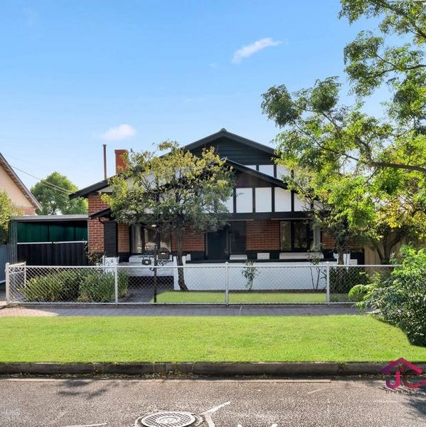 Suburban house with a manicured lawn and trees under a clear blue sky.