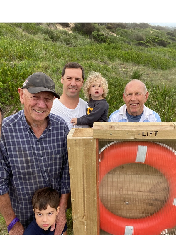 three men and two infants standing around a lifebuoy