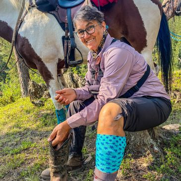 woman with bandage on her leg. Horse in the background.