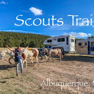 Girl jumping for joy, 3 horses behind her, a truck camper and horse trailer in background.