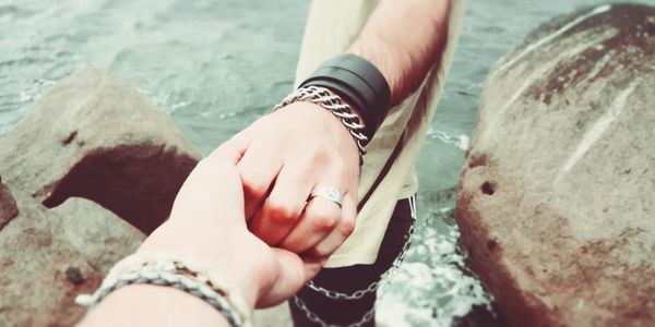 Hands reaching across water and rocks indicating help, support and guidance