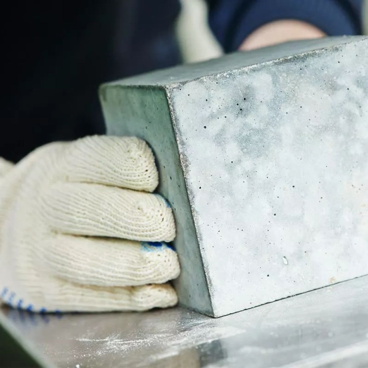Worker wearing gloves holding a concrete block.