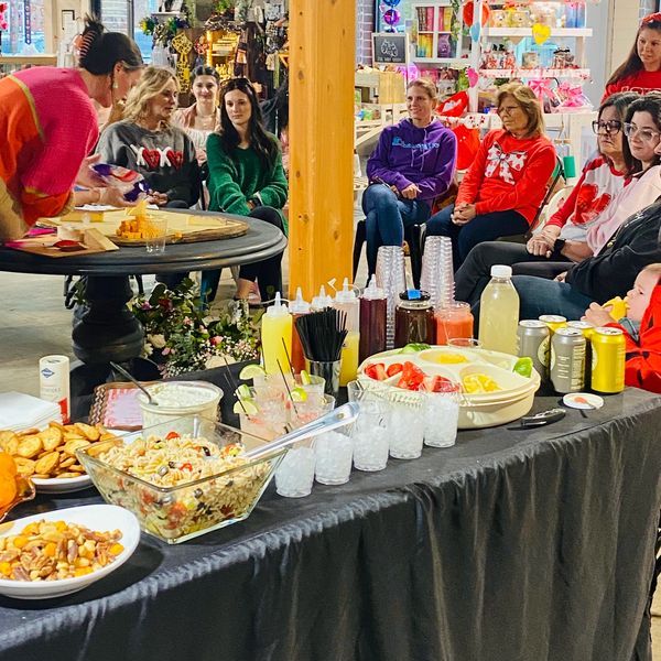 Group of people sitting and food spread on a table indoors.