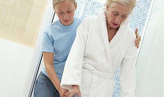 Caregiver assisting elderly woman with walking aid.