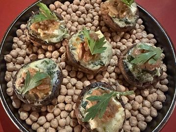 Stuffed mushrooms garnished with walnuts and herbs on a bed of chickpeas.