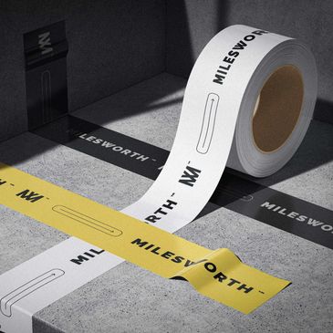 Rolls of branded tape with 'MILESWORTH' text in black, white, and yellow colors on a concrete surface.