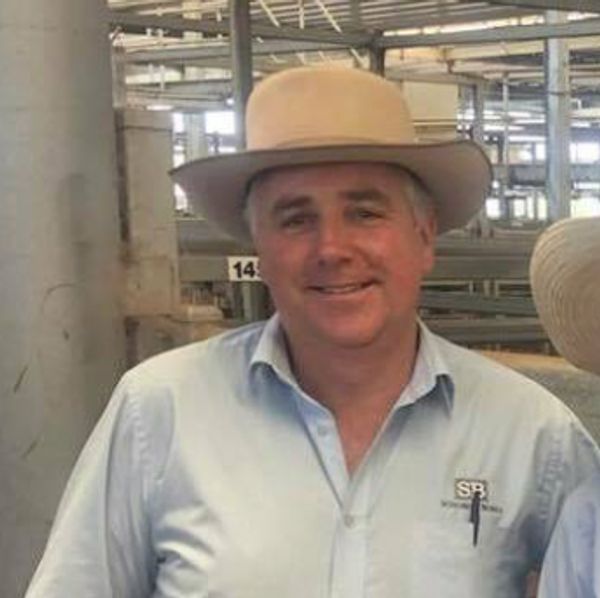 Man wearing a beige hat and light blue shirt smiling indoors.