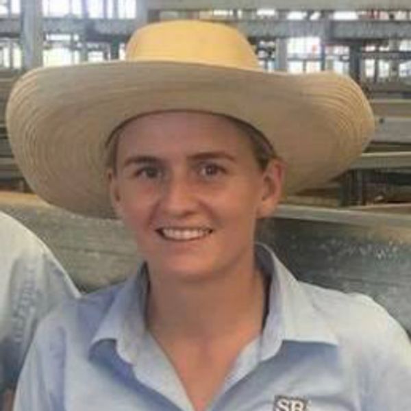 Smiling person wearing a wide-brimmed hat and light blue shirt.