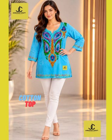 Woman wearing a blue embroidered cotton top with white pants.