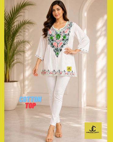 Woman wearing white cotton top with floral embroidery and white pants.