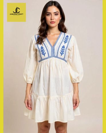Woman wearing a white dress with blue embroidery from Jawahar Craft.