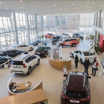 Modern car showroom with various vehicles and customers inside.