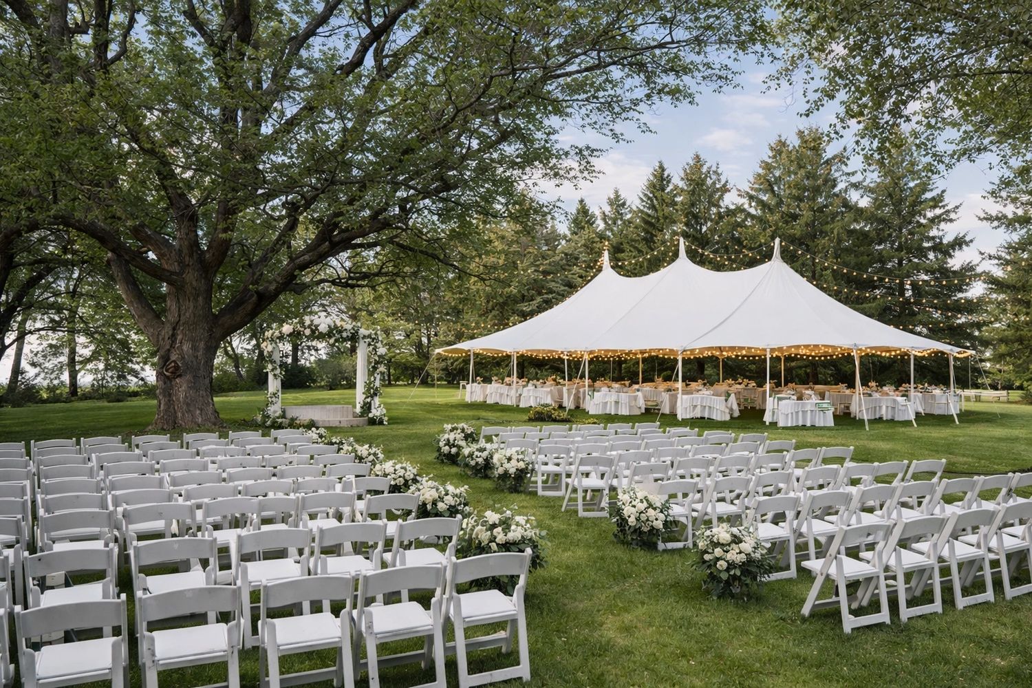 Outdoor wedding venue setup at Raven House Events shows the outdoor event space with white chairs and a large tent adorned with lights. Raven Restrooms the luxury restroom rental is behind the tent and trees in the outdoor event spaces