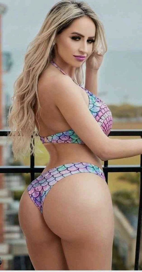 Woman posing outdoors in a colorful mermaid-scale bikini.