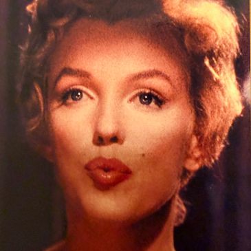 Close-up of a woman with curly blonde hair and red lipstick.