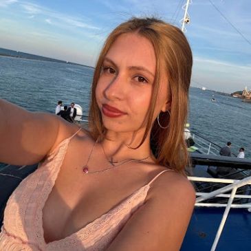 Young woman taking a selfie on a boat with water in the background.
