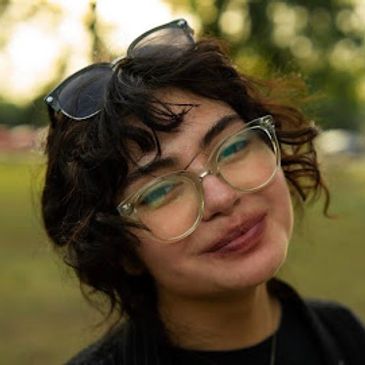 Smiling person wearing glasses outdoors.