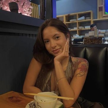 Woman smiling at a restaurant table with food.
