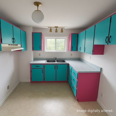 A kitchen with teal and pink cabinets and a double sink under a window.