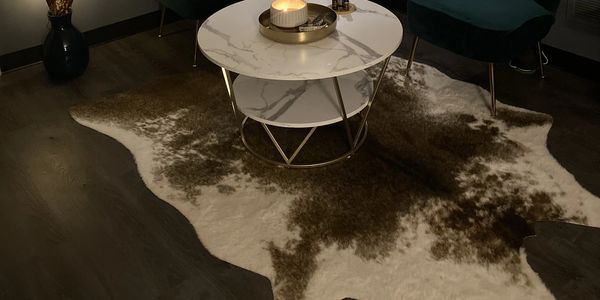 Modern living room with a marble-top coffee table on a cowhide rug.