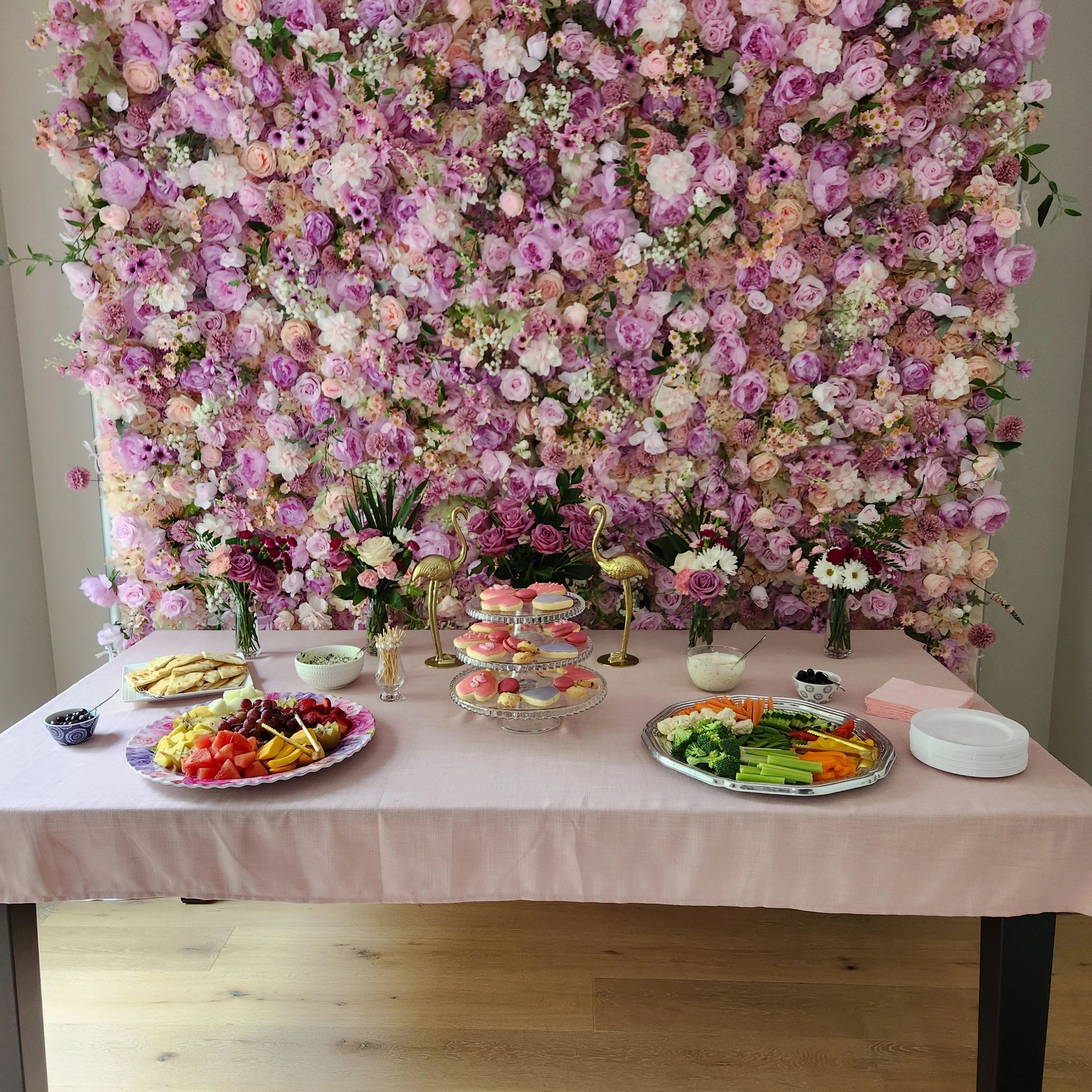 Elegant floral backdrop with a table of assorted snacks and desserts.
