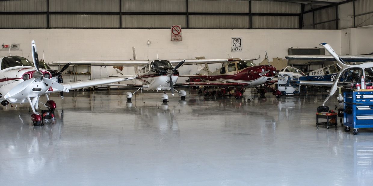 Several small airplanes parked inside a clean, spacious hangar.