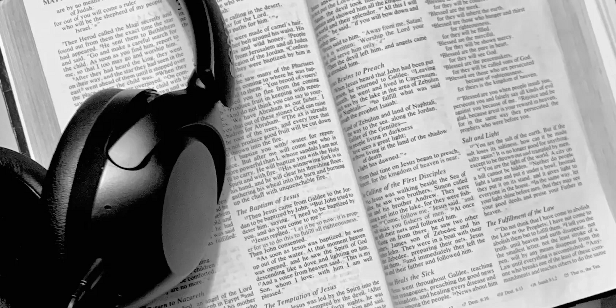 Black headphones resting on an open Bible, highlighting Matthew chapters.