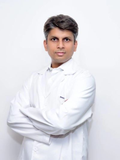 Man in a white lab coat posing with arms crossed.