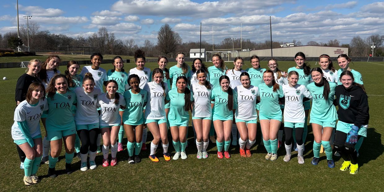 Two girls' soccer teams posing together on a sunny field.