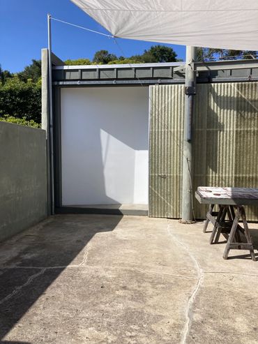 Outdoor concrete area with a table and shade sail on a sunny day.